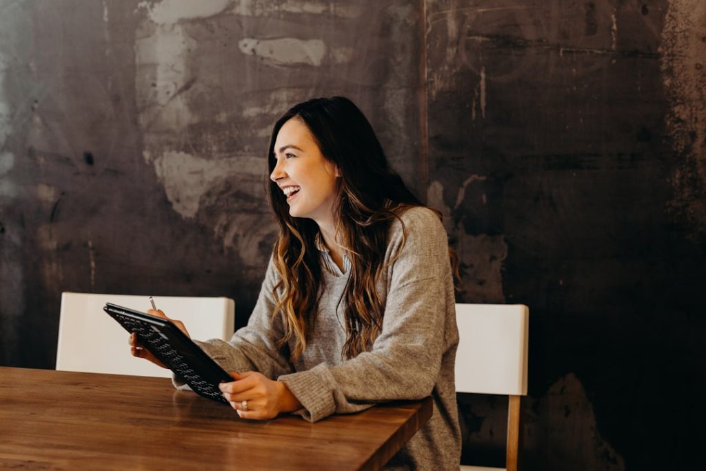 woman-sitting-around-table-holding-tablet-jbwcenourcg